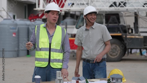 Architect and Civil Engineer Discussing Building Plans with Architectural Models and Blueprint on Worktable