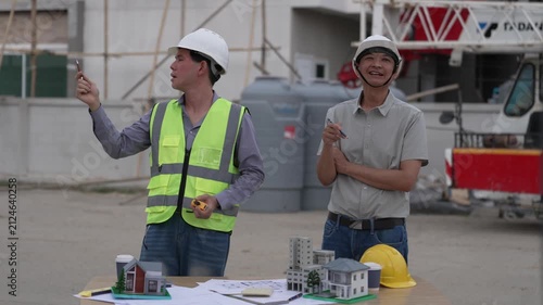 Architect and Civil Engineer Discussing Building Plans with Architectural Models and Blueprint on Worktable