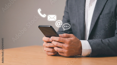 Businessman using a smartphone with digital communication icons. Excellent commercial asset for corporate networking and customer support