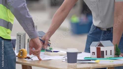 Architect and Civil Engineer Discussing Building Plans with Architectural Models and Blueprint on Worktable