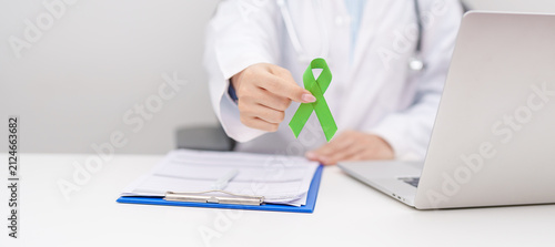 Foto Doctor give lime Green Ribbon for concept of May Celiac Awareness month, Lyme disease, September Lymphoma, Mental Health Awareness month and October Liver cancer