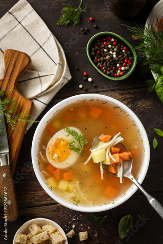 Chicken soup with boiled egg and croutons in a bowl. Chicken broth. Dinner rustic composition