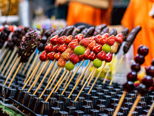 Rows of Glazed Candied Fruit Skewers Strawberry Grape Chocolate Banana