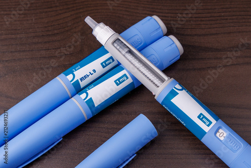Blue Semaglutide GLP-1 pen injector on dark wooden table surface, subcutaneous medical therapy for obesity and type 2 diabetes concept style