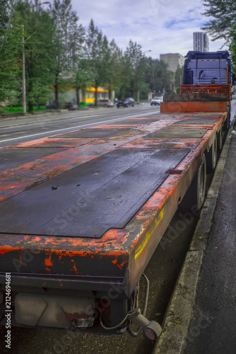 An old truck is parked on the street on a summer day