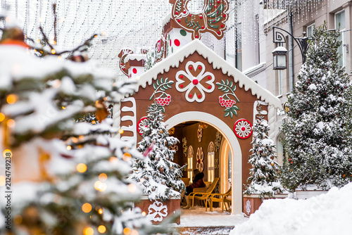 A gingerbread house with a sign among snow‑covered Christmas trees in Kamergersky Lane in Moscow. Concept for the New Year 2027.