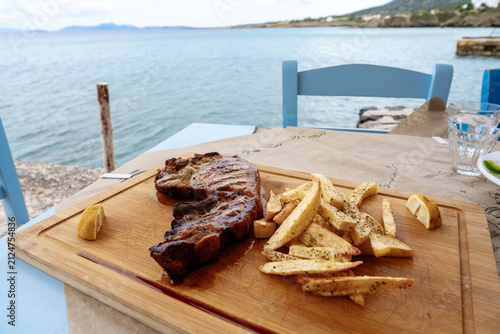 Fotografie Delicious grilled steak with fries overlooking the tranquil sea in Moutsouna, Na