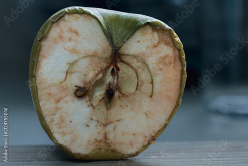 Cross section of an aging green apple showing natural browning and oxidation. Soft natural light and shallow depth of field emphasize texture, decay, and the passage of time.