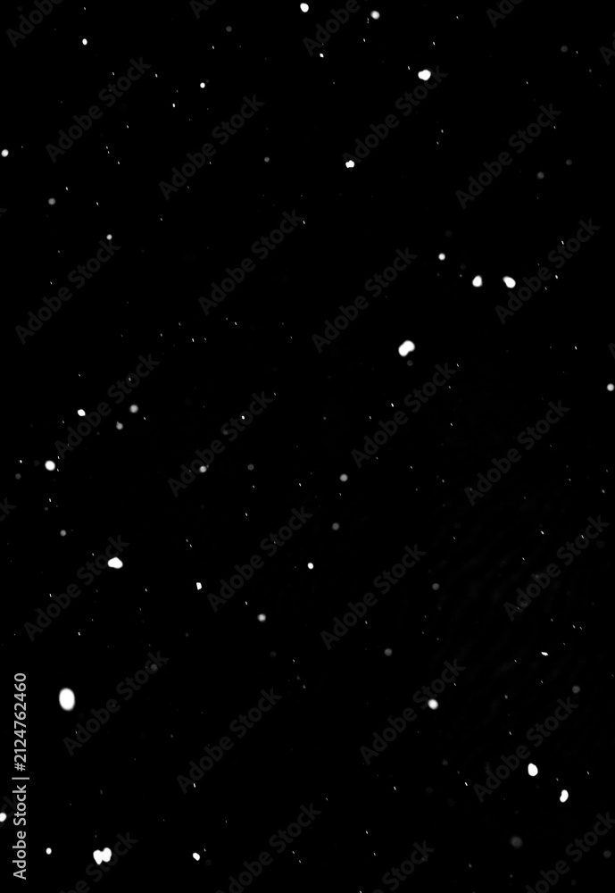 Fotografie Snowflakes falling on dark black background, isolated winter effect texture