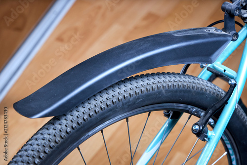 фотографія Close up of bicycle rear wheel featuring black plastic mudguard, knobby tire, li