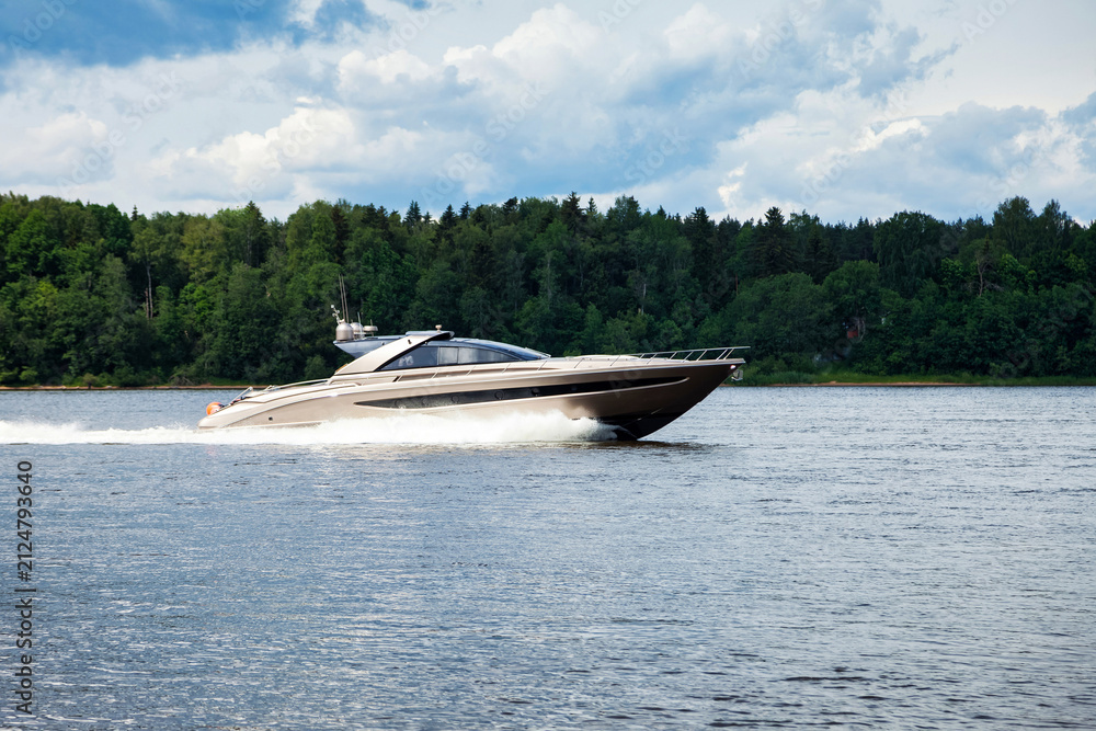 Fototapeta premium Luxury Speedboat Gliding Over Tranquil Waters Under a Cloudy Sky