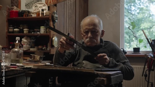 Elderly craftsman working in his old workshop, carefully restoring collectible Japanese bladed weapons