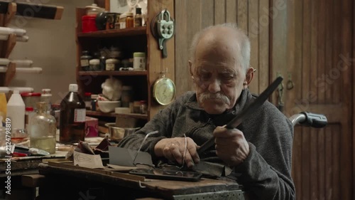 Elderly craftsman working in his old workshop, carefully restoring collectible Japanese bladed weapons