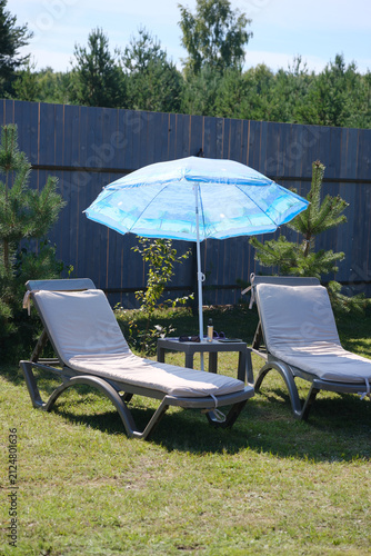 Fotografía Sun loungers with blue umbrella in backyard garden