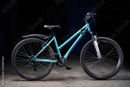 Foto Turquoise step-through mountain bike stands studio-lit against a dark backdrop