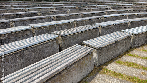 Fotografía Rows of weathered concrete bleachers with wooden slats forming empty seating in an outdoor amphitheater