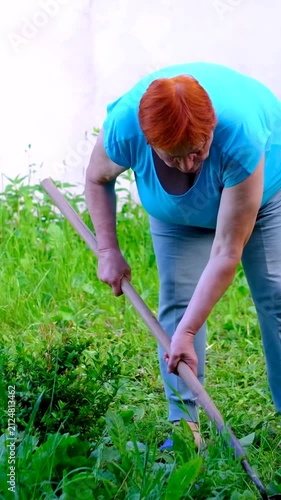 adult woman tends her home garden using simple hand tools, showing everyday gardening, vegetable cultivation, outdoor work and a healthy rural lifestyle. Close up.