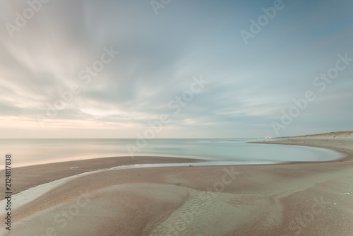 Fotografía Calm beach shoreline at dusk with soft clouds