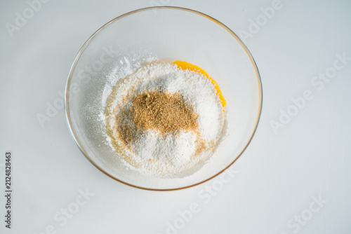 Obraz na płótnie Baking ingredients in glass bowl with flour and egg yolk from top view