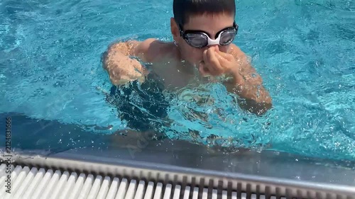 Child holding nose and diving into swimming pool water