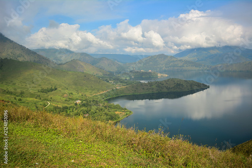Calm lake surrounded by lush green hills under a partly cloudy blue sky captures a breathtaking natural panorama of a lake reflecting the sky amidst rolling hills relates to nature conservation