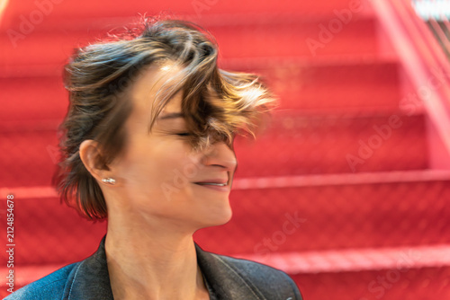 Bild auf Leinwand Happy businesswoman laughing with windblown hair against red industrial backgrou