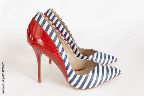 Elegant striped navy high heel shoes with red accents on white studio backdrop