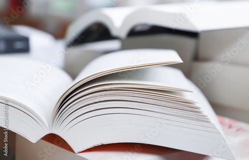 stack of books, close up. Open book on the table in library. Back to school concept. Open book on table with blur bookshelf background