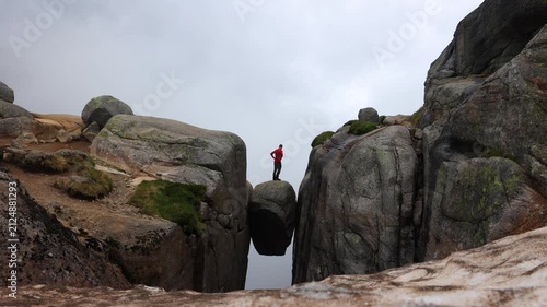 Solo male hiker stepping onto Kjeragbolten rock in southern Norway