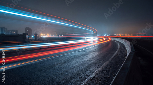 Cuadro en lienzo Dramatic long exposure photograph of a curved highway at night with dynamic blue, red, and white light trails