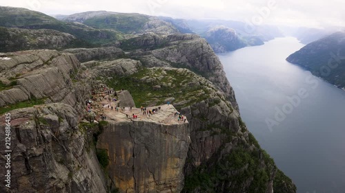 Many hikers walking on Preikestolen above a large fjord in Norway
