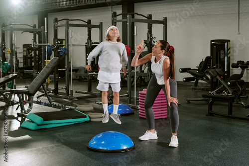 Canvastavla Caucasian female trainer instructing Caucasian boy jumping on balance platform i