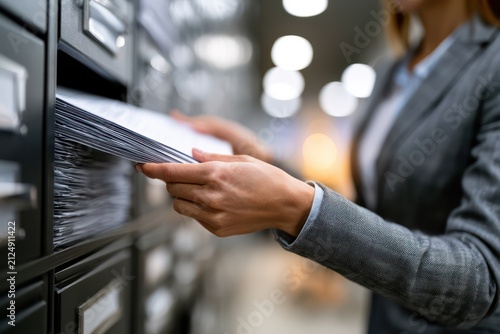 Side view of secretary organizing paper documents into cabinet