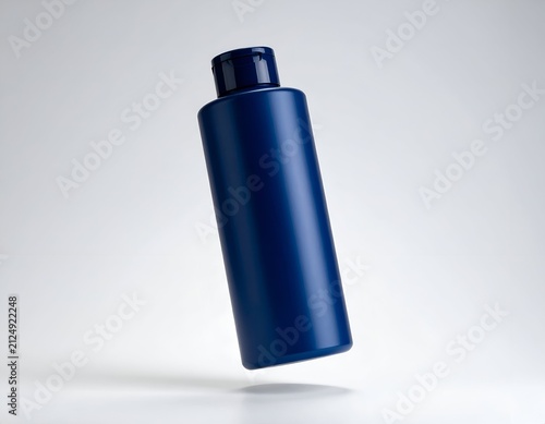 A dark blue cylindrical bottle with a flip-top cap is floating against a white background