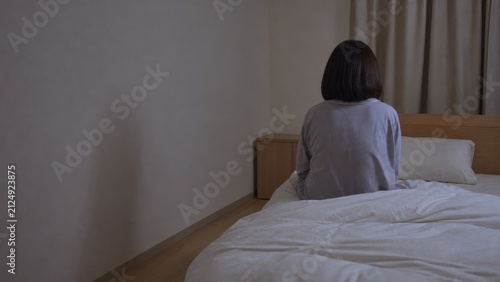 Fototapeta 夜の寝室で眠れずベッドに座る女性の後ろ姿