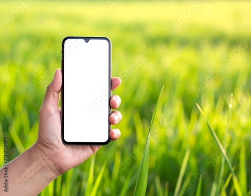 A hand holds a smartphone with a blank white screen, against a blurred green field