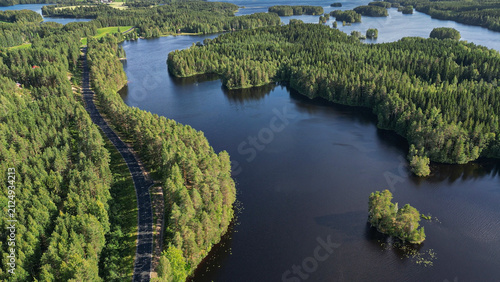 Aerial drone view above a forested lakeside road. Lake Kankarisvesi, small islands, peninsulas and dense woodland near Jämsä in Central Finland. Scenic Finnish Lakeland landscape