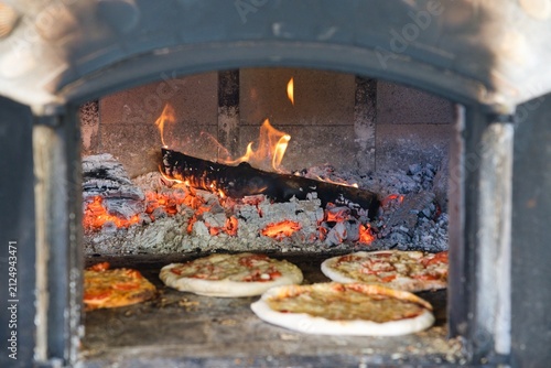 Traditional wood fired pizza oven with fireplace and stoked firewood.