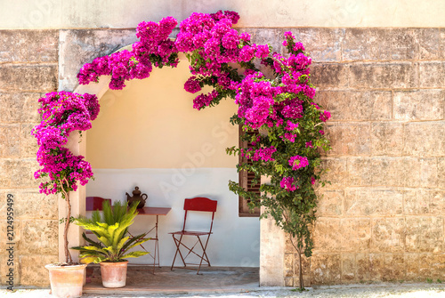 Mediterranean Impression – Entrance by an old sand-lime brick wall with a seating area and blooming bougainvilleas - 28987