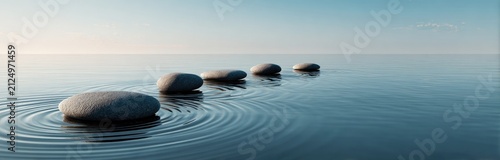 Serene image of smooth stones aligned in calm water with light reflections. Ripples radiate outwards, creating visual tranquility and zen