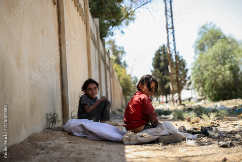 фотографія Thoughtful poor children sitting near a wall