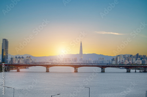 SEOUL, SOUTH KOREA - December 22, 2025: Scenery of Lotte Tower with bridge railway transport over the han river and city town landscape on golden sky cuold clear before sunset