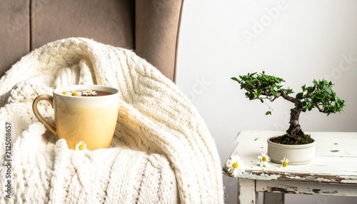 Cozy scene with yellow mug of chamomile tea and bonsai tree