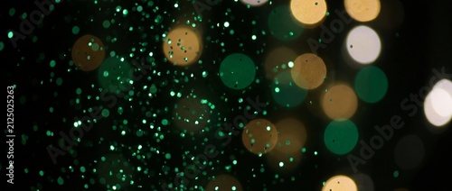 Abstract Emerald Green Glitter Particles and Golden Bokeh Lights Background