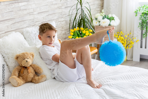 Cute little preschool child, cute blond boy, playing in bed with many teddy bears, handmade amigurumi toys, enjoying toy game
