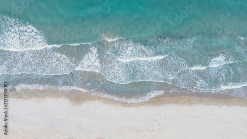 Foto Aerial top down view of turquoise ocean waves creating white foam patterns on sa