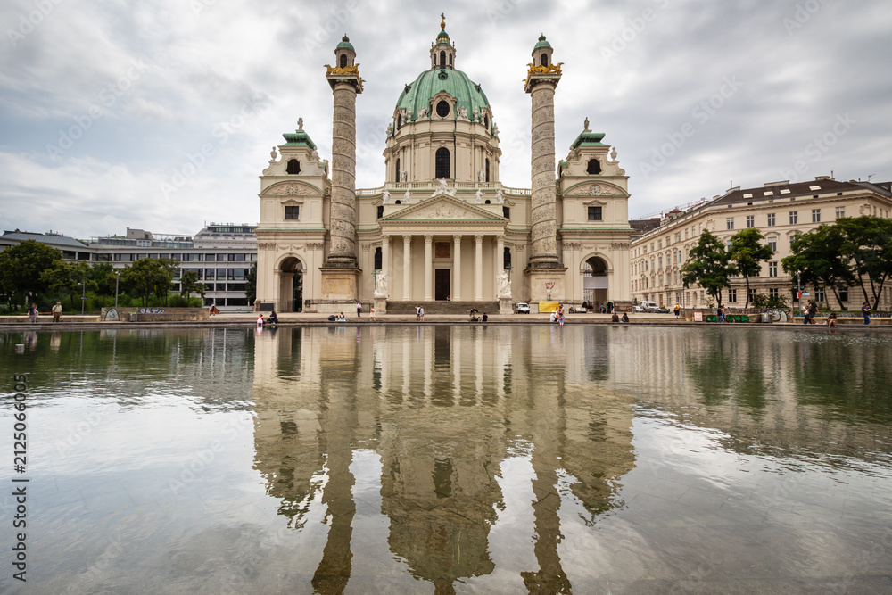 Naklejka premium Karlskirchen Baroque church reflecting on still water pool in Vienna Austria on overcast day