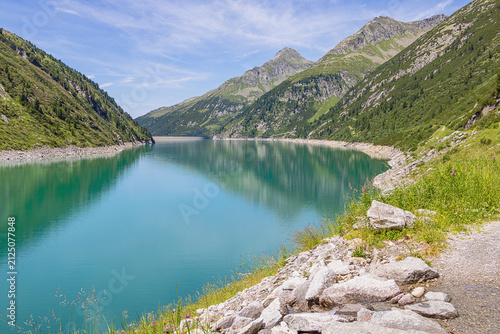 The mountain ridges around the Zillergrund dam Lake with with water reflections and the dam crown in the background