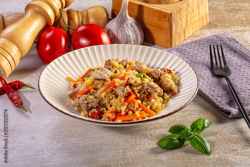Fotografie Traditional pilaf with meat, carrots, and spices on a rustic wooden table