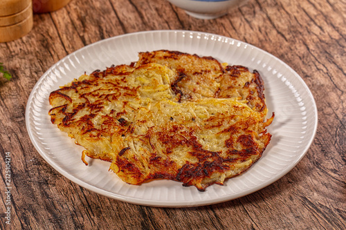 Konstfotografi Crispy golden hash brown on white plate over rustic wooden table